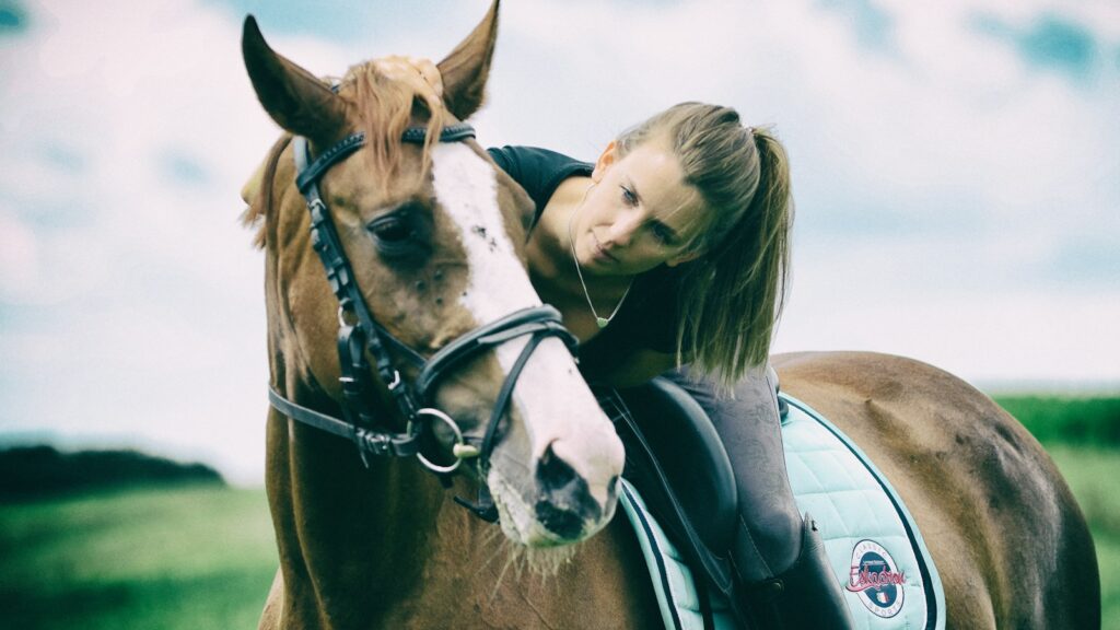 woman in white shirt riding on brown horse during daytime