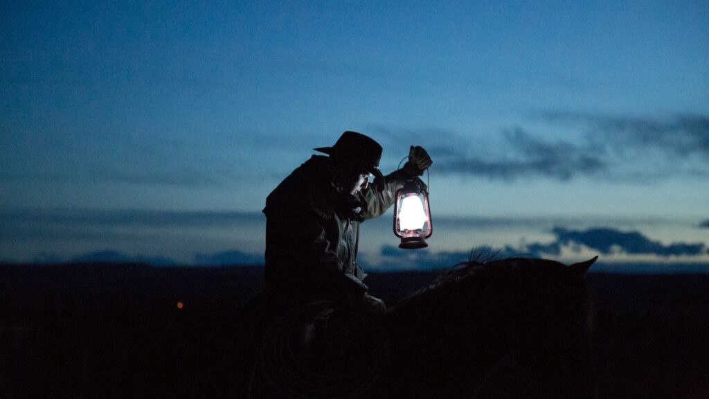 horseback riding cowboy holding a lamp