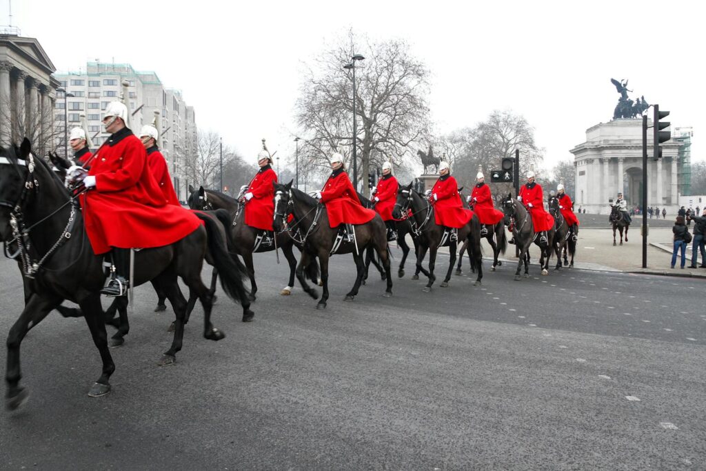 Horse Guards in red uniforms riding through London during a ceremonial parade.