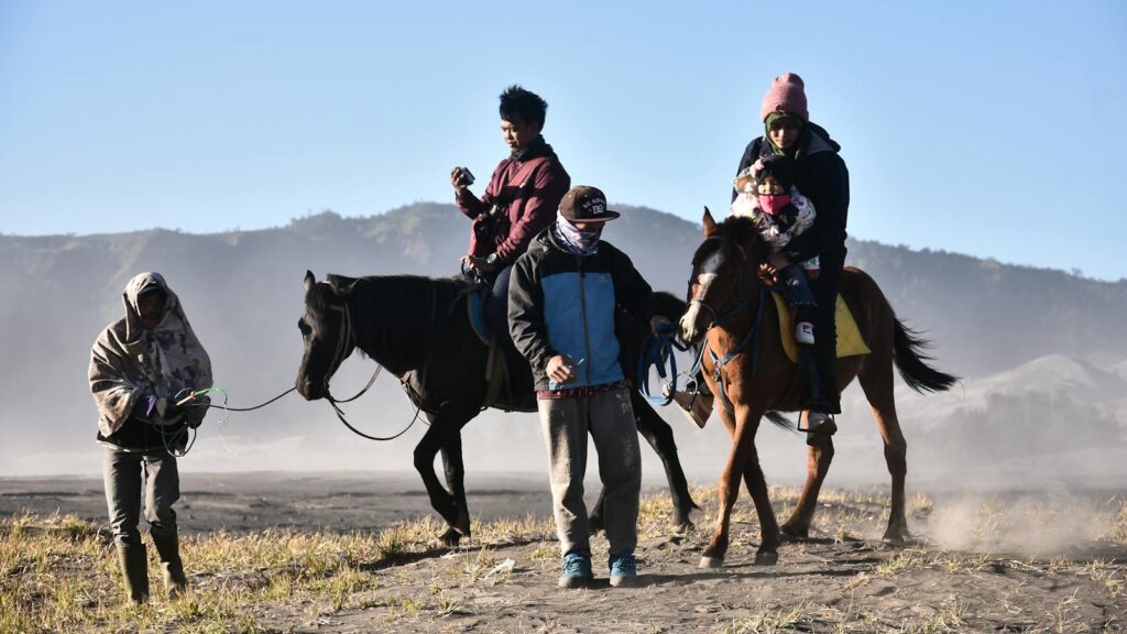 A group of people riding horses in the scenic landscape of Mount Bromo, Indonesia.