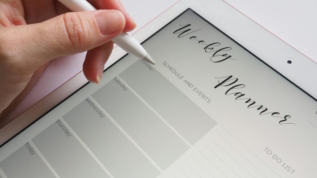 A stylus writing in a digital weekly planner on a tablet screen, ideal for organization.