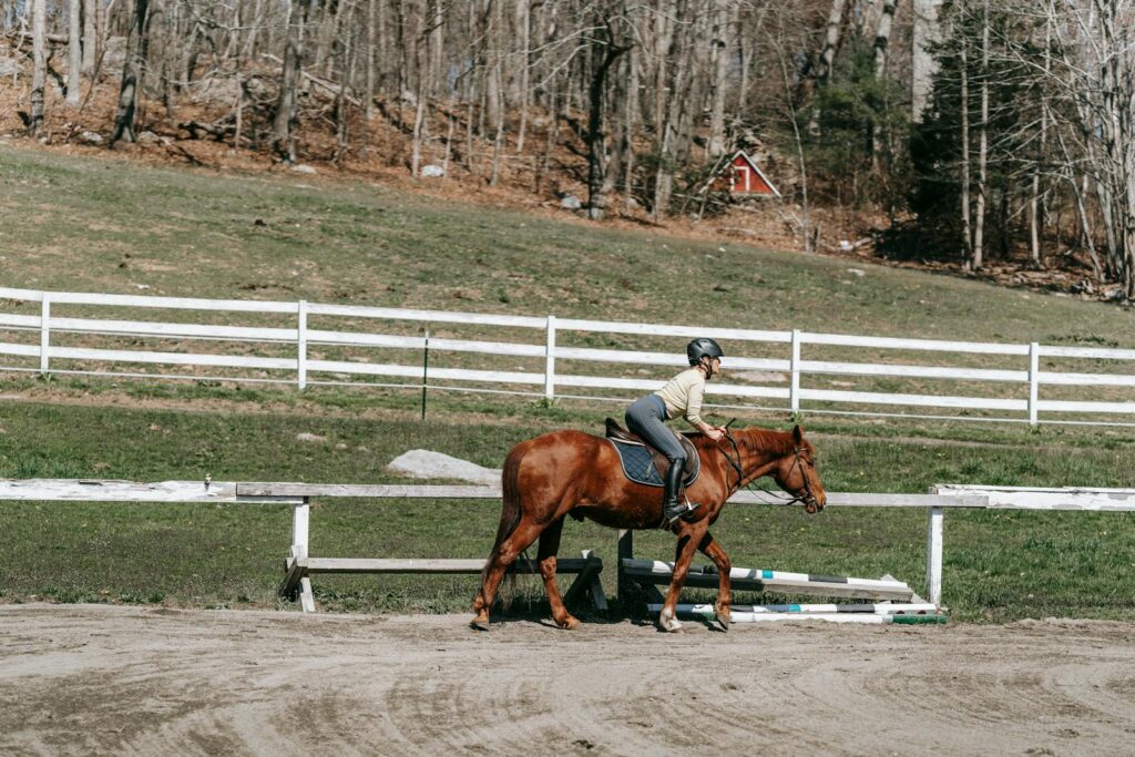 A woman riding a horse in a rustic paddock scene outdoors in spring.