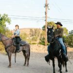 Two people riding horses outdoors, showcasing equestrian lifestyle and nature.