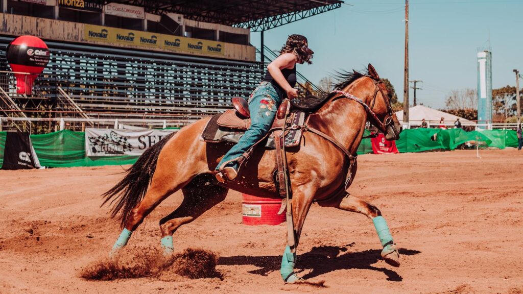 Woman riding horse at an outdoor rodeo competition, showcasing skill and passion.