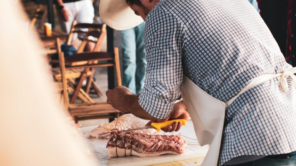 Man slicing pork at an outdoor barbecue event in Recife, Brazil.