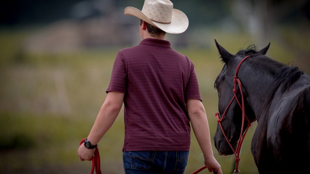a man in a cowboy hat walking a horse
