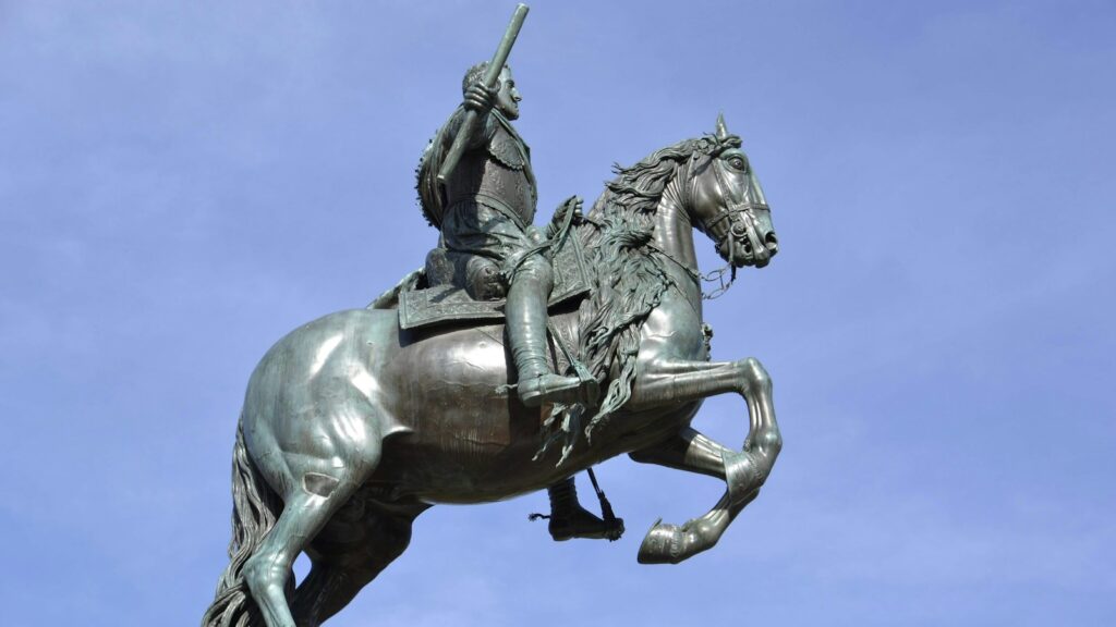 man riding on horse statue under blue sky