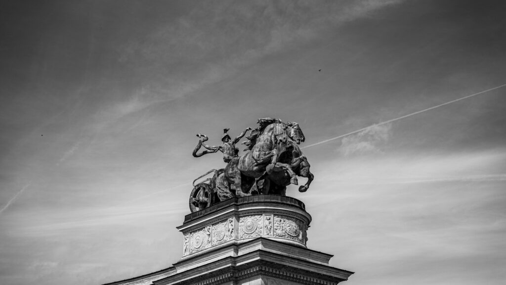 a black and white photo of a statue on top of a building