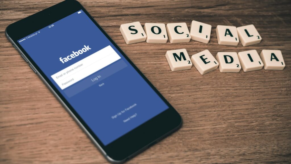 space gray iPhone 6 with Facebook log-in display near Social Media scrabble tiles