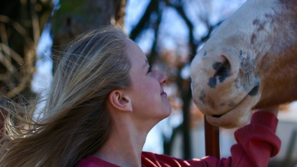 portrait of woman looking at beige horse