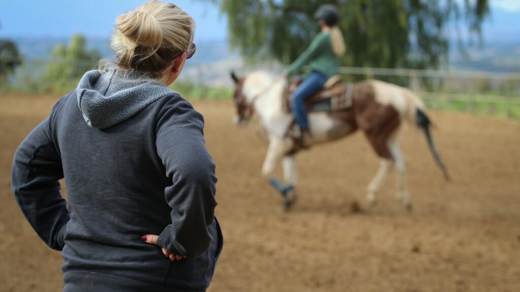 woman watching man riding horse