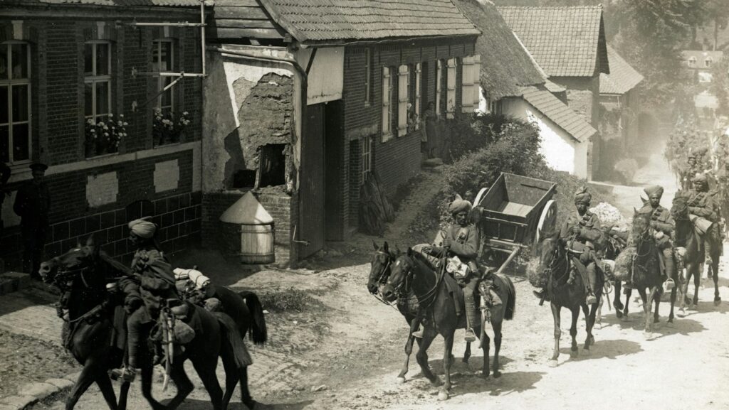 people riding horse beside houses grayscale photography