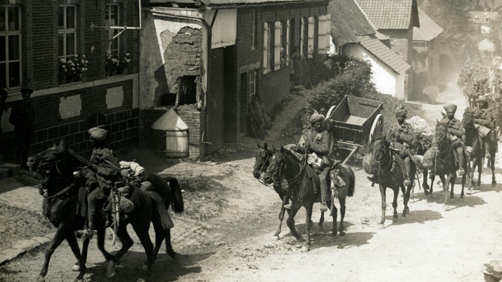 people riding horse beside houses grayscale photography