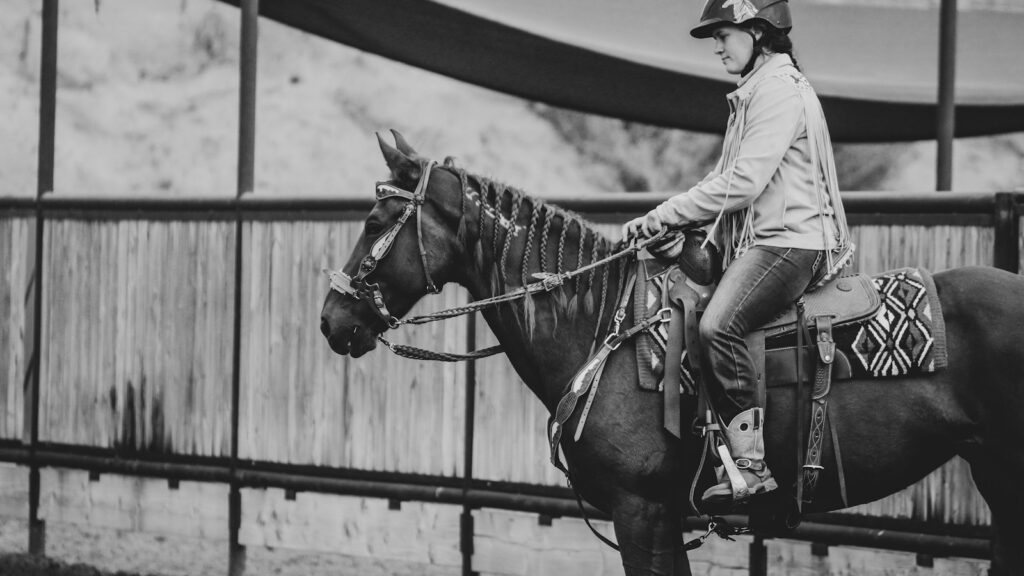 grayscale photo of man riding horse