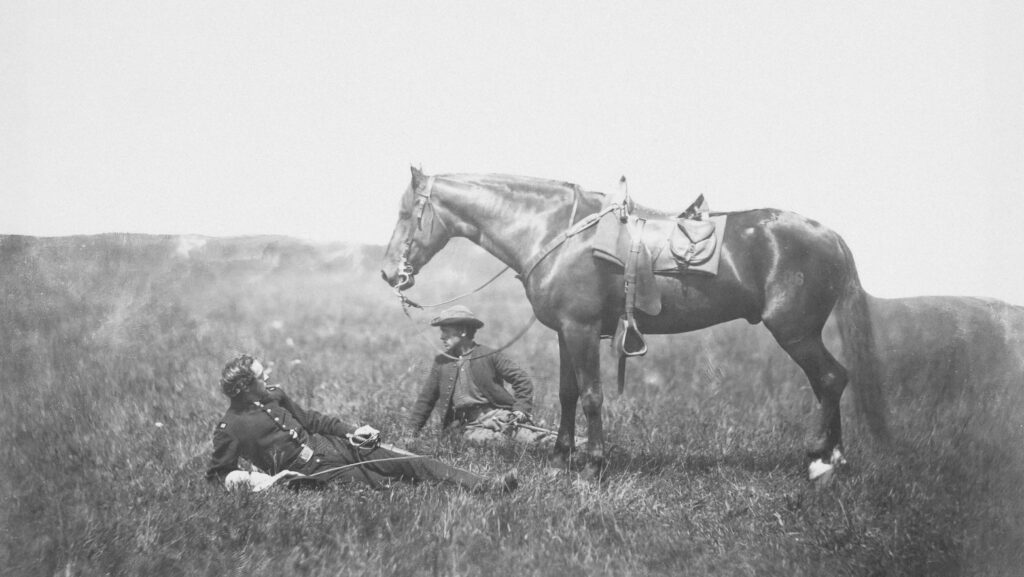 a man sitting in a field next to a horse