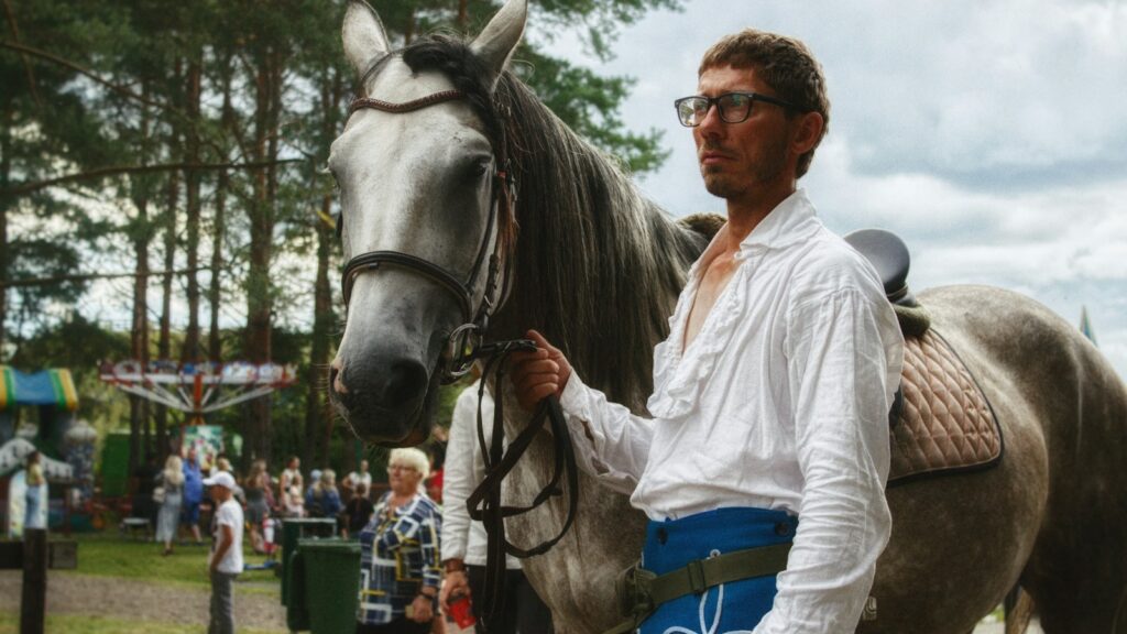 a man standing next to a brown horse