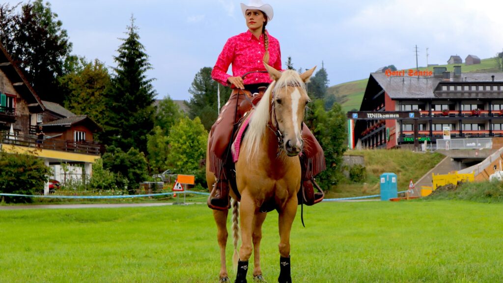 girl in pink long sleeve shirt riding brown horse during daytime